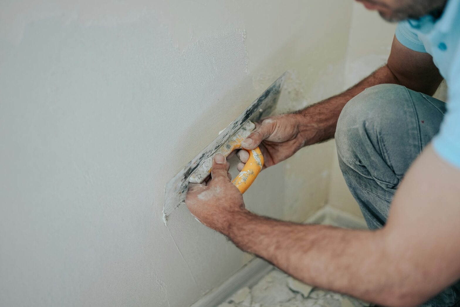 Plasterer applying wet plaster to an uneven wall for a smooth, crack-free result.